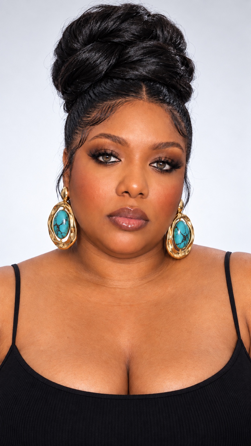Joy Kelechi wearing a black top and turquoise statement earrings with her hair in an elegant updo